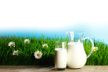 Glass of milk and jar on flower meadow