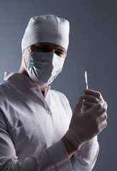 Male doctor in cap, mask and rubber medical gloves holding scalp