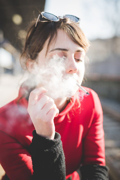 Young woman smoking cigarette while waiting on railway platform
