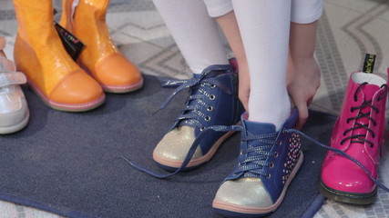 trying on new shoes for junior girls in children shoe store