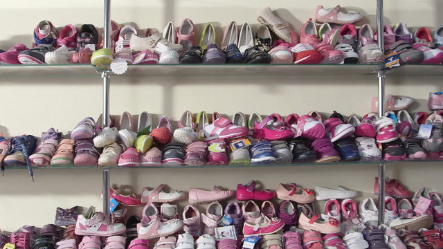 Shelf  with shoes for kids in the children shoe store pan shot