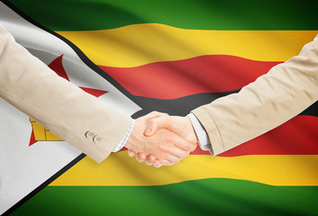 Businessmen handshake with flag on background - Zimbabwe