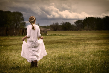 Girl wearing a dress walking in a pasture