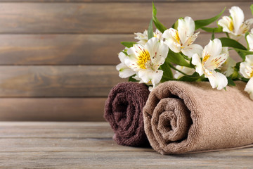 Obraz na płótnie Canvas Towels with beautiful flowers on wooden background
