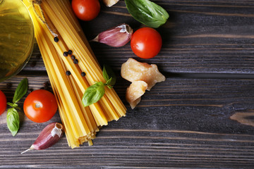 Raw pasta with cheese and vegetables on wooden background