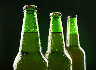 Glass bottles of beer on dark green background