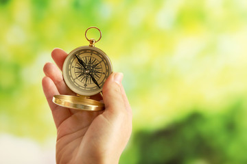 Female hand with compass on bright blurred background
