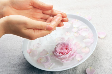 Female hands with bowl of aroma spa water on table, closeup