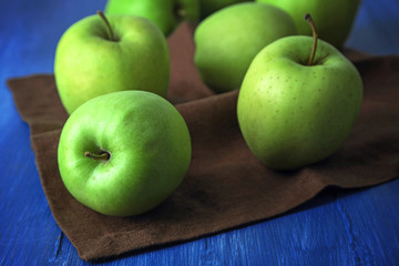 Green apples on wooden table with napkin, closeup