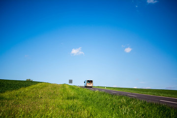 Ab in den Urlaub, mit dem Reisebus aufs Land vorbei an grünen Feldern und blauem Himmel
