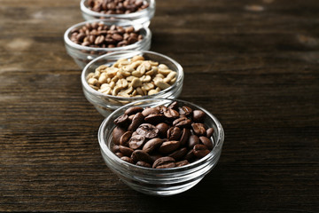 Coffee beans in saucers on wooden background