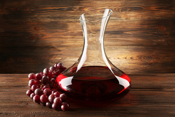 Glass carafe of wine on wooden background