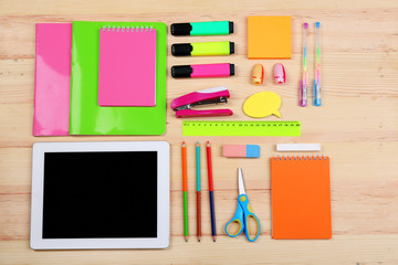 Digital tablet with stationery on wooden background