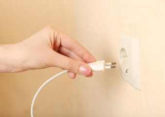 Hand putting plug in electricity socket close up