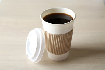 Paper cup of coffee on wooden background
