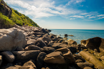 Fototapeta na wymiar rocks on the beach with blue sky and mountain