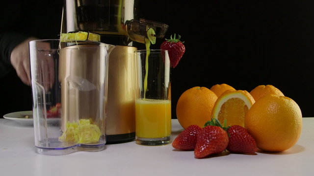 Making fresh fruit juice strawberry orange using juicer