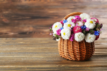 Beautiful colorful daisy in wicker basket on wooden background