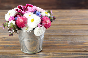 Colorful daisy in metal bucket on wooden background