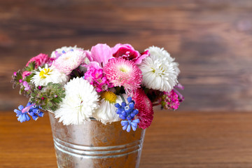 Colorful daisy in metal bucket on wooden background