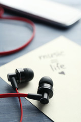 Earphones with text Music - life on sticker on wooden table, closeup