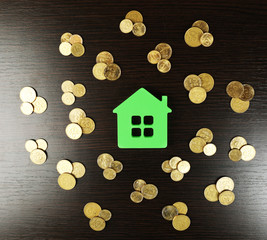 Model of house with coins on wooden table, closeup