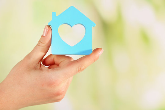 Female hand with model of house on blurred background