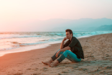 Fototapeta na wymiar Handsome sexy and sad man sitting at beach.