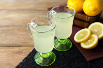 Still life with lemon juice and sliced lemons on wooden background