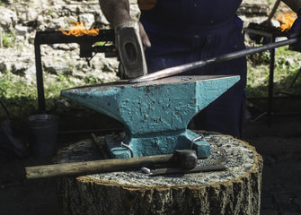 Blacksmith forges iron on anvil