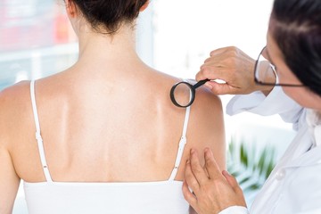 Doctor examining patient with magnifying glass