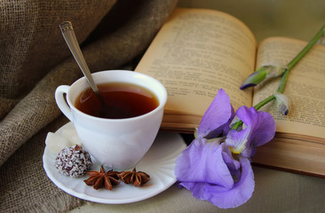 Cup of tea, open book and flower iris.
