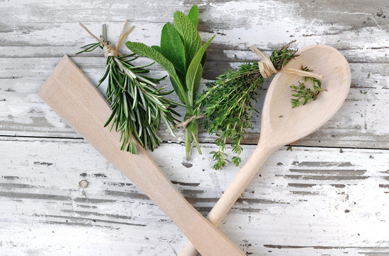 herbes aromatiques et cuillère en bois sur planche 