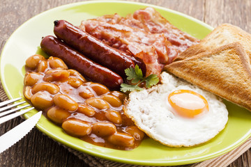 Full english breakfast with bacon, sausage, fried egg, baked bea