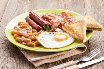 Full english breakfast with bacon, sausage, fried egg, baked bea