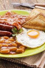Full english breakfast with bacon, sausage, fried egg, baked bea