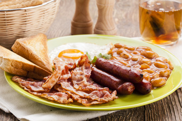 Full english breakfast with bacon, sausage, fried egg, baked bea