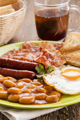Full english breakfast with bacon, sausage, fried egg, baked bea