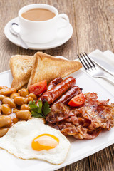 Full english breakfast with bacon, sausage, fried egg, baked bea