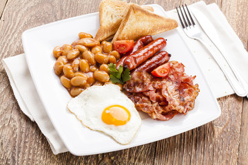 Full english breakfast with bacon, sausage, fried egg, baked bea