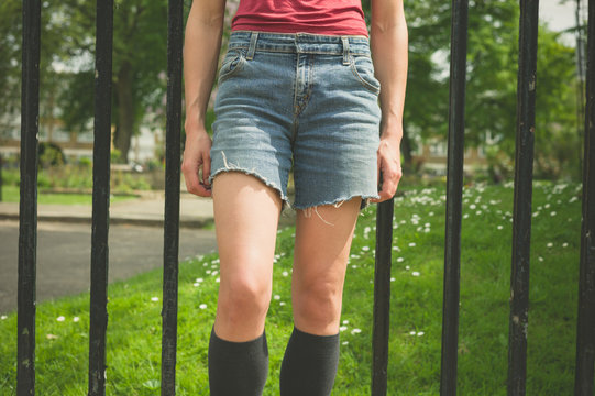 Young woman standing by gate outside park