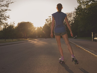 Young woman roller skating in park at sunset