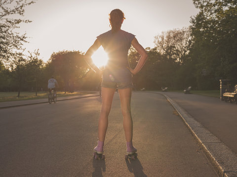 Young woman wearing roller skates in park at sunset