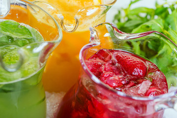 a mix of several bright colored delicious cold lemonade carafes