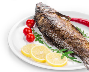 Grilled carp with vegetables on plate.