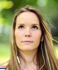 Obraz premium Female student girl outside in park listening to music on headph