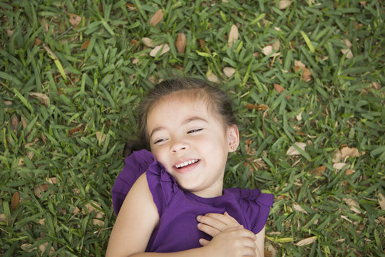 A child lying on her back on the grass.