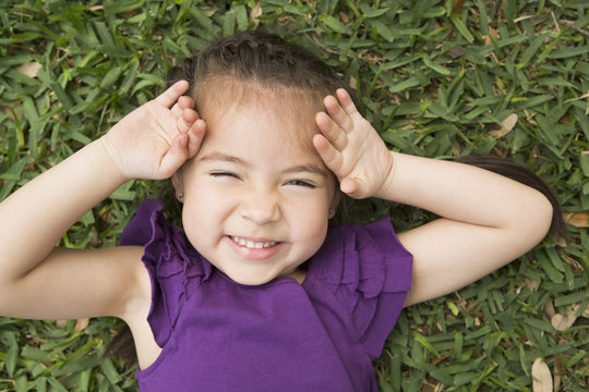 A girl lyiing on the grass with her hands by her head, laughing. 