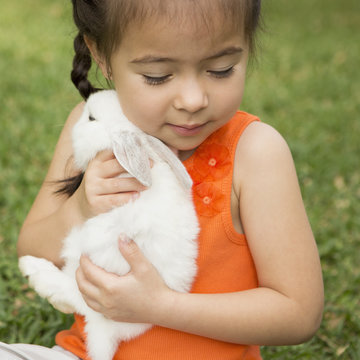 A child holding a large white rabbit. 