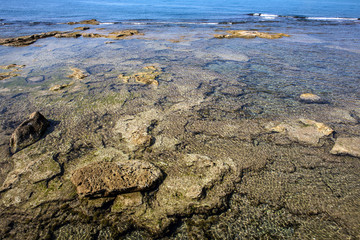Fototapeta na wymiar surfacing rocks into blue transparent sea